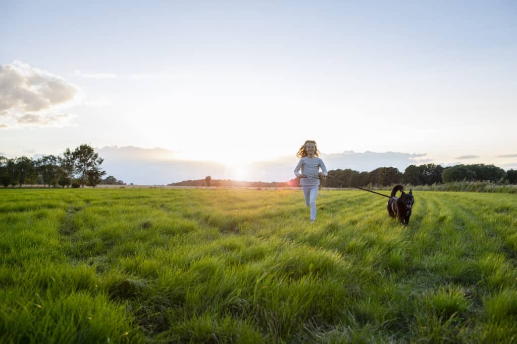 Girl and her dog relocating to Denmark running through a field